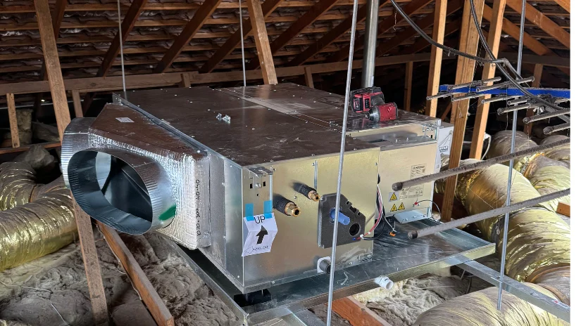 Air Conditioning unit in ceiling space with rafters and insulation visible being installed for ducted air conditioning