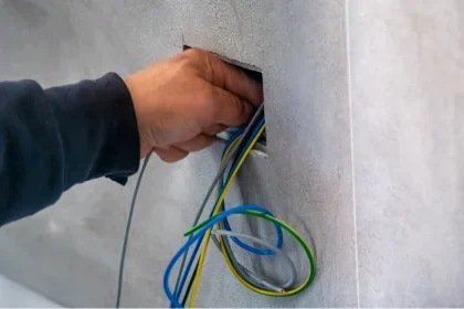 Hand of COYCO electrician reaching into wall cavity to finish wiring a home